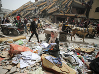 A Palestinian woman is searching for her belongings after her apartment was destroyed in an Israeli raid, amid the ongoing conflict between...