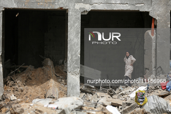 A Palestinian woman is searching for her belongings after her apartment was destroyed in an Israeli raid, amid the ongoing conflict between...