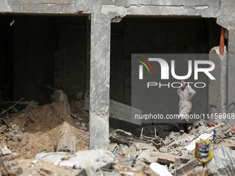 A Palestinian woman is searching for her belongings after her apartment was destroyed in an Israeli raid, amid the ongoing conflict between...