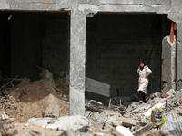 A Palestinian woman is searching for her belongings after her apartment was destroyed in an Israeli raid, amid the ongoing conflict between...