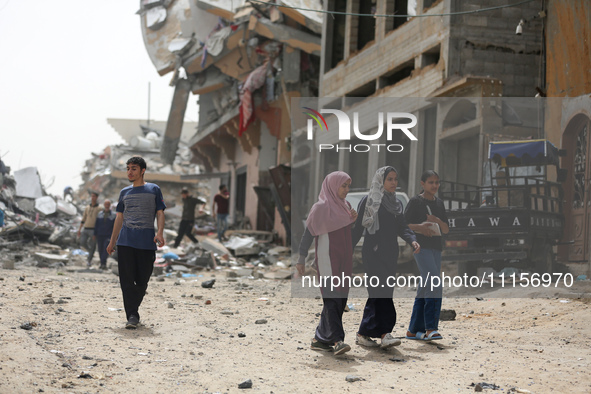 Palestinians are gathering around residential buildings that were destroyed during an Israeli raid, amid the ongoing conflict between Israel...