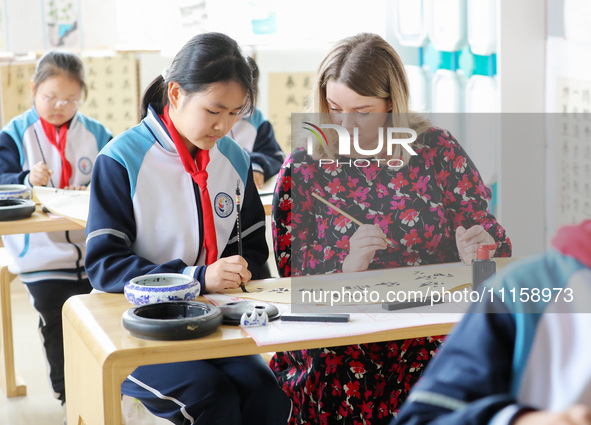 A foreign friend from South Africa is learning calligraphy with primary school children in Qingdao, Shandong Province, China, on April 19, 2...