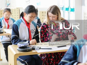 A foreign friend from South Africa is learning calligraphy with primary school children in Qingdao, Shandong Province, China, on April 19, 2...