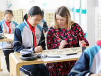 A foreign friend from South Africa is learning calligraphy with primary school children in Qingdao, Shandong Province, China, on April 19, 2...