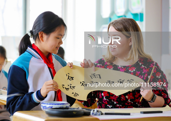 A foreign friend from South Africa is learning calligraphy with primary school children in Qingdao, Shandong Province, China, on April 19, 2...