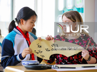 A foreign friend from South Africa is learning calligraphy with primary school children in Qingdao, Shandong Province, China, on April 19, 2...