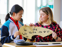 A foreign friend from South Africa is learning calligraphy with primary school children in Qingdao, Shandong Province, China, on April 19, 2...