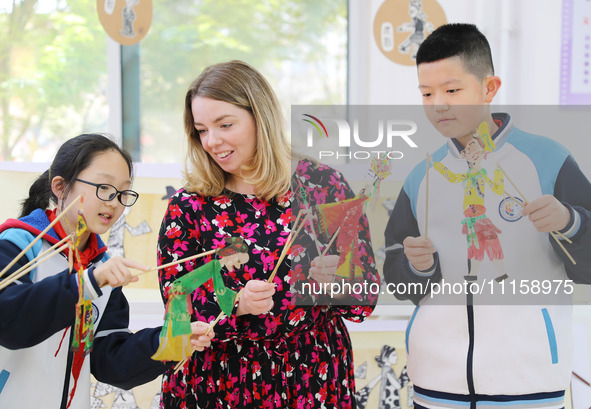 A foreign friend from South Africa is experiencing Chinese shadow play with primary school children in Qingdao, Shandong Province, China, on...