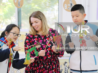 A foreign friend from South Africa is experiencing Chinese shadow play with primary school children in Qingdao, Shandong Province, China, on...