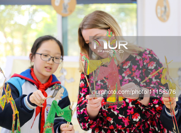 A foreign friend from South Africa is experiencing Chinese shadow play with primary school children in Qingdao, Shandong Province, China, on...