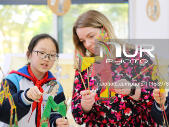 A foreign friend from South Africa is experiencing Chinese shadow play with primary school children in Qingdao, Shandong Province, China, on...