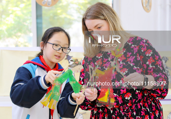 A foreign friend from South Africa is experiencing Chinese shadow play with primary school children in Qingdao, Shandong Province, China, on...