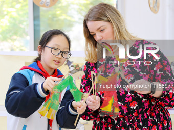 A foreign friend from South Africa is experiencing Chinese shadow play with primary school children in Qingdao, Shandong Province, China, on...