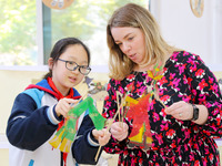 A foreign friend from South Africa is experiencing Chinese shadow play with primary school children in Qingdao, Shandong Province, China, on...