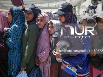 Displaced Palestinians are gathering to receive food at a donation point in Deir al-Balah, central Gaza Strip, on April 19, 2024, amid ongoi...