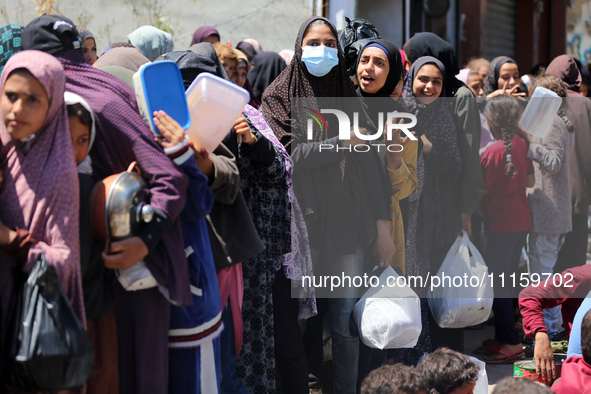 Displaced Palestinians are gathering to receive food at a donation point in Deir al-Balah, central Gaza Strip, on April 19, 2024, amid ongoi...