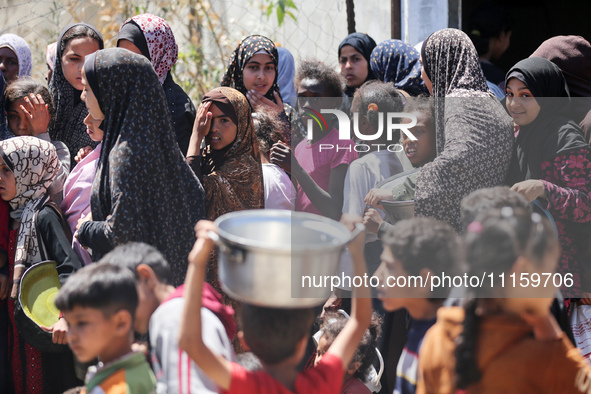 Displaced Palestinians are gathering to receive food at a donation point in Deir al-Balah, central Gaza Strip, on April 19, 2024, amid ongoi...