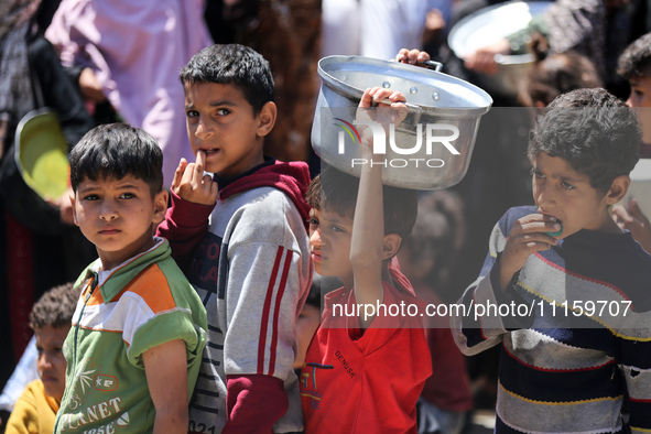 Displaced Palestinians are gathering to receive food at a donation point in Deir al-Balah, central Gaza Strip, on April 19, 2024, amid ongoi...