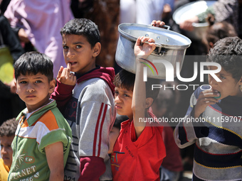 Displaced Palestinians are gathering to receive food at a donation point in Deir al-Balah, central Gaza Strip, on April 19, 2024, amid ongoi...