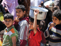 Displaced Palestinians are gathering to receive food at a donation point in Deir al-Balah, central Gaza Strip, on April 19, 2024, amid ongoi...