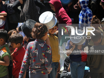 Displaced Palestinians are gathering to receive food at a donation point in Deir al-Balah, central Gaza Strip, on April 19, 2024, amid ongoi...