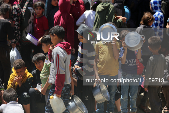 Displaced Palestinians are gathering to receive food at a donation point in Deir al-Balah, central Gaza Strip, on April 19, 2024, amid ongoi...