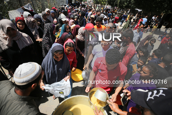 Displaced Palestinians are receiving cooked food rations at a donation point in Deir al-Balah in the central Gaza Strip, on April 19, 2024,...