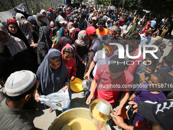 Displaced Palestinians are receiving cooked food rations at a donation point in Deir al-Balah in the central Gaza Strip, on April 19, 2024,...