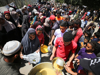 Displaced Palestinians are receiving cooked food rations at a donation point in Deir al-Balah in the central Gaza Strip, on April 19, 2024,...