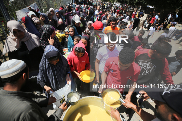 Displaced Palestinians are receiving cooked food rations at a donation point in Deir al-Balah in the central Gaza Strip, on April 19, 2024,...