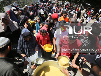 Displaced Palestinians are receiving cooked food rations at a donation point in Deir al-Balah in the central Gaza Strip, on April 19, 2024,...