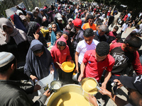 Displaced Palestinians are receiving cooked food rations at a donation point in Deir al-Balah in the central Gaza Strip, on April 19, 2024,...