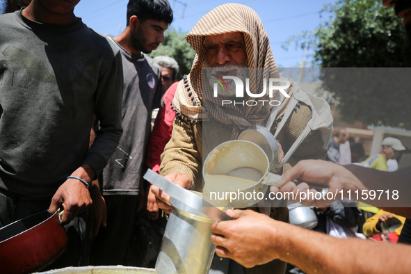 Displaced Palestinians are receiving cooked food rations at a donation point in Deir al-Balah in the central Gaza Strip, on April 19, 2024,...