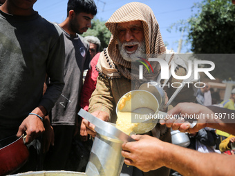 Displaced Palestinians are receiving cooked food rations at a donation point in Deir al-Balah in the central Gaza Strip, on April 19, 2024,...