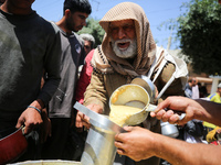 Displaced Palestinians are receiving cooked food rations at a donation point in Deir al-Balah in the central Gaza Strip, on April 19, 2024,...