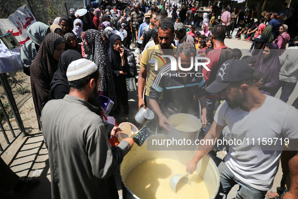 Displaced Palestinians are receiving cooked food rations at a donation point in Deir al-Balah in the central Gaza Strip, on April 19, 2024,...