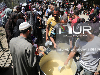 Displaced Palestinians are receiving cooked food rations at a donation point in Deir al-Balah in the central Gaza Strip, on April 19, 2024,...