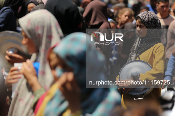 Displaced Palestinians are receiving cooked food rations at a donation point in Deir al-Balah in the central Gaza Strip, on April 19, 2024,...