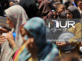 Displaced Palestinians are receiving cooked food rations at a donation point in Deir al-Balah in the central Gaza Strip, on April 19, 2024,...