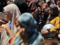 Displaced Palestinians are receiving cooked food rations at a donation point in Deir al-Balah in the central Gaza Strip, on April 19, 2024,...