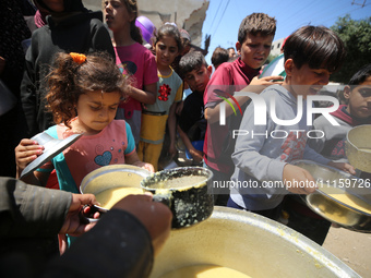 Displaced Palestinians are receiving cooked food rations at a donation point in Deir al-Balah in the central Gaza Strip, on April 19, 2024,...