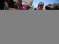 Displaced Palestinians are receiving cooked food rations at a donation point in Deir al-Balah in the central Gaza Strip, on April 19, 2024,...