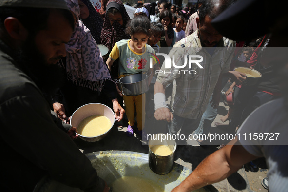 Displaced Palestinians are receiving cooked food rations at a donation point in Deir al-Balah in the central Gaza Strip, on April 19, 2024,...