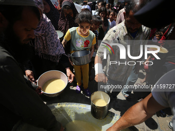 Displaced Palestinians are receiving cooked food rations at a donation point in Deir al-Balah in the central Gaza Strip, on April 19, 2024,...