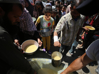 Displaced Palestinians are receiving cooked food rations at a donation point in Deir al-Balah in the central Gaza Strip, on April 19, 2024,...