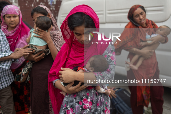 Women are holding their children while standing outside the Dhaka Shishu (Children) Hospital after a fire broke out inside the intensive car...