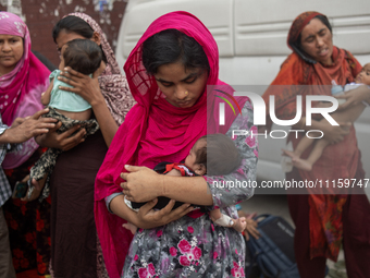 Women are holding their children while standing outside the Dhaka Shishu (Children) Hospital after a fire broke out inside the intensive car...