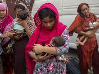 Women are holding their children while standing outside the Dhaka Shishu (Children) Hospital after a fire broke out inside the intensive car...