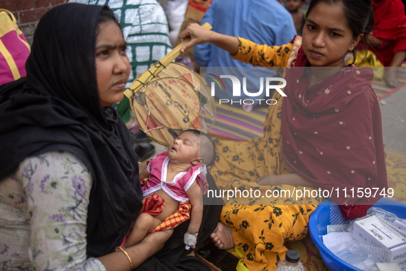 Women are holding their children while standing outside the Dhaka Shishu (Children) Hospital after a fire broke out inside the intensive car...