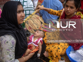 Women are holding their children while standing outside the Dhaka Shishu (Children) Hospital after a fire broke out inside the intensive car...